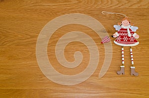 Red and white wooden angel Christmas tree decoration holding heart on wood background with copy space