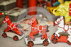 Red and white wooden horse toy for sale in a traditional handicraft store during Christmas market