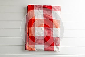 Red and white wrinkly vichy fabric lying on white wooden background