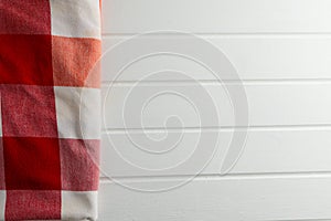 Red and white wrinkly vichy fabric lying on white wooden background