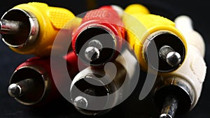 Red, white and yellow male cinch plugs, on black background