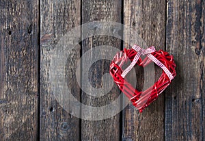 Red wicker heart on a wooden brown background. Red bow. Love