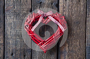 Red wicker heart on a wooden brown background. Red bow. Love