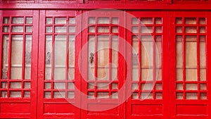 Red window brown wood wall.Detail of colorful window on old traditional house