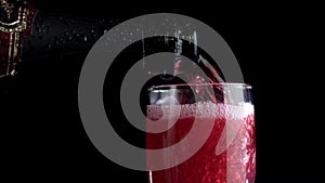 Red wine being poured into a glass of black background. Slow motion