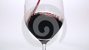 Red wine being poured into a wine glass a white background.