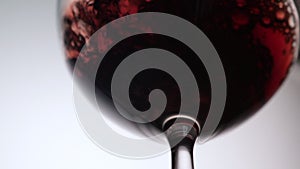 Red wine being poured into a wine glass a white background.