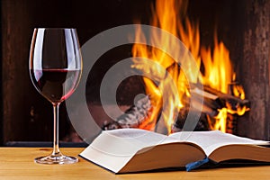 Red wine and book at cozy fireplace