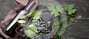 Red Wine bottle and basket of black grapes and glass of red wine on dark rustic concrete background. Flat lay wine composition Red