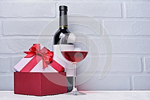 Red wine bottle with empty label, glass for tasting and gift box for romantic surprise