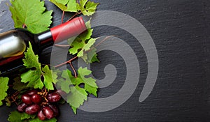 Red wine bottle and fresh grapes on black background