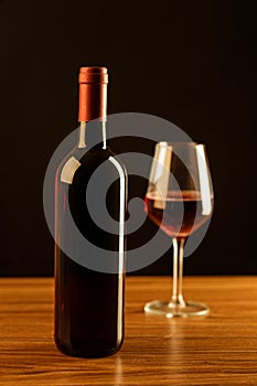 Red wine bottle with glass on black background