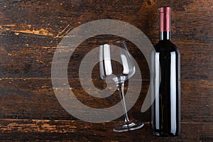 Red wine bottle and glass goblet on a wooden background. Alcoholic drink. Top view