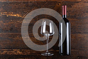 Red wine bottle and glass goblet on a wooden background. Alcoholic drink. Top view