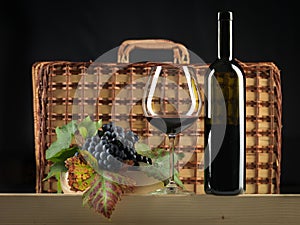 Red wine bottle, glass, grapes, picnic basket photo