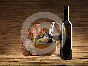 Red wine bottle, glass, grapes, wicker background photo