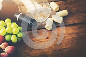 Red wine bottle with glass and grapes on wooden background