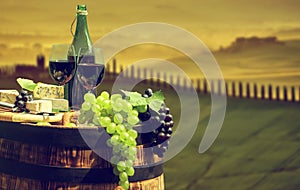 Red wine bottle and glass on old barrel.