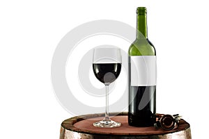 Red wine bottle and glass on a wooden barrel