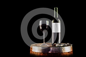 Red wine bottle and glass on a wooden barrel - isolated on black