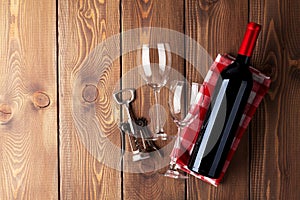 Red wine bottle, glasses and corkscrew on wooden table