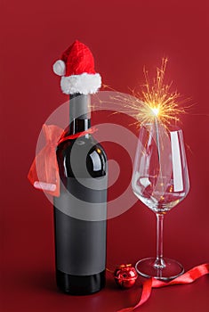 Red wine bottle mockup with black label wearing little red Santa and wine glass with sparklers