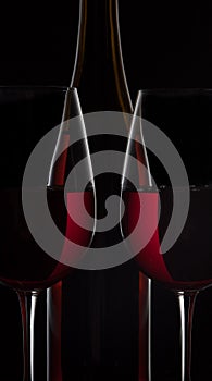 Red wine bottle and two wine glasses on black background