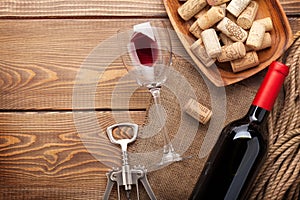 Red wine bottle, wine glass, bowl with corks and corkscrew