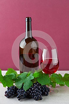 Red wine bottle with wineglass and ripe grapes