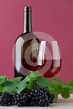 Red wine bottle with wineglass and ripe grapes