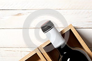 Red wine bottle in a wooden box rest on a white wooden table with copy space for your text