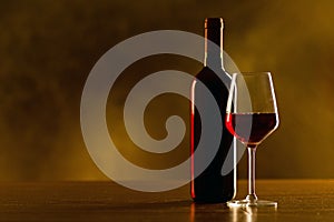 Red wine bottles and glass on wooden table and black background