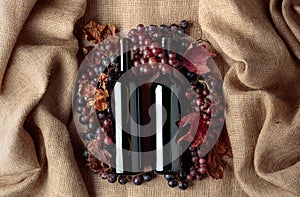 Red wine bottles and grapes with dried up vine leaves.