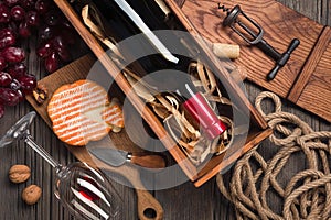 Red wine in a box with a glass, corkscrew and cream cheese on a wooden old table. Top view with space for your greetings