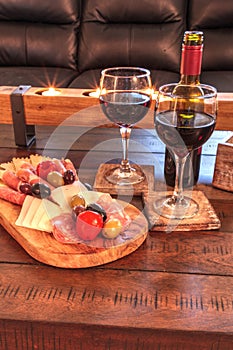 Red wine with Charcuterie board on rustic wood with candles behind a spread of prosciutto panino