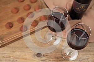 Red wine and chocolate truffles on wooden table, above view