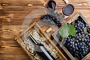 Red Wine composition on brown wooden table. Top view. Red wine bottle corkscrew corks wine glasses black ripe grapes in