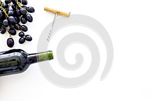 Red wine concept. Glass bottle with beverage near bunch of grapes and corkscrew on white background top view space for