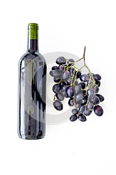 Red wine concept. Glass bottle with beverage near bunch of grapes on white background top view