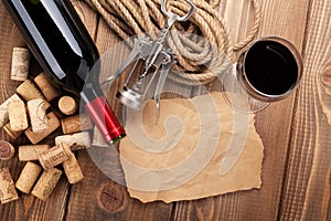 Red wine, corks, corkscrew and piece of paper