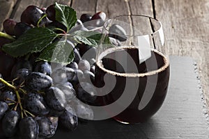 Red wine and dark grapes on a wooden background