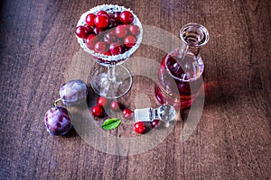 Red wine in a decanter. cherry in a glass. plum on the table