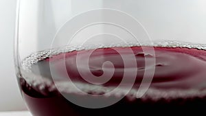 Red wine drop falling down into drink glass on white background, nutrition health-care concept, shooting with high speed camera