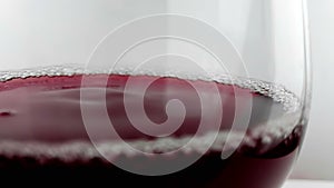 Red wine drop falling down into drink glass on white background, nutrition health-care concept, shooting with high speed camera