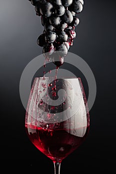 Red wine flows down the grape cluster into the glass