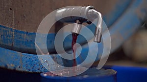 Red wine flows out from tap of a tank inside a wine cellar