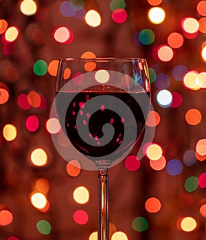 Red wine glass against christmas lights bokeh background