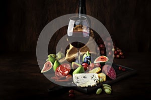 Red wine glass and appetizers, cheese, salami, figs, grapes, vintage wooden table background, selective focus, copy space photo