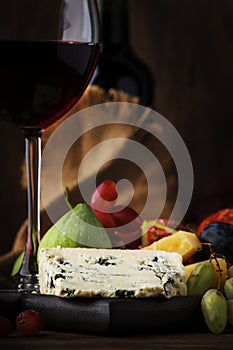 Red wine glass and appetizers, cheese, salami, figs, grapes, vintage wooden table background, selective focus, copy space