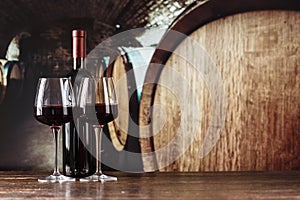 Red wine in a glass on the background of barrels in the cellar